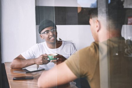 Foto de Siempre disfruto de nuestras charlas. dos jóvenes hablando mientras toman un café juntos en un café - Imagen libre de derechos