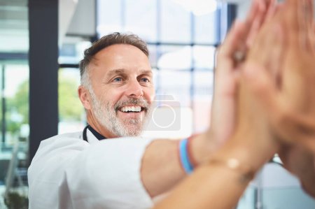 Téléchargez les photos : Mon équipe me rendra fier. un médecin mature donnant à ses collègues un high five dans un hôpital - en image libre de droit