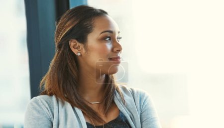 Photo for She loves the view from her office. an attractive young businesswoman looking out of her office window - Royalty Free Image