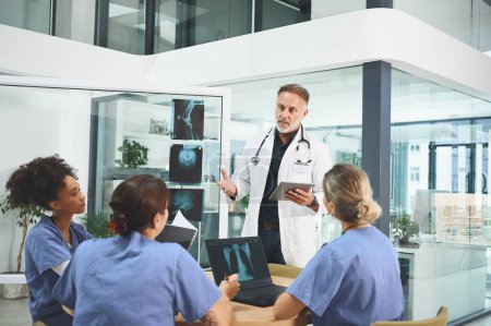 Foto de Interpretar las pruebas con su equipo. un médico maduro dirigiendo una discusión con sus colegas en un hospital - Imagen libre de derechos