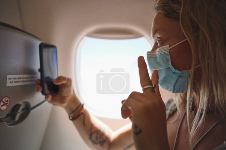 Téléchargez les photos : La paix. une jeune femme prenant un selfie dans l'avion - en image libre de droit