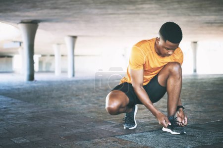 Photo for Time to get a grip on good health. a young man tying his shoelaces during a workout against an urban background - Royalty Free Image