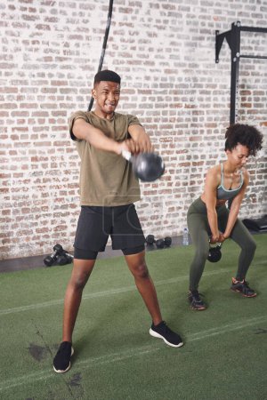 Foto de Ponerse en forma es mucho más difícil de lo que parece. dos jóvenes deportistas que usan kettlebells mientras hacen ejercicio en el gimnasio - Imagen libre de derechos