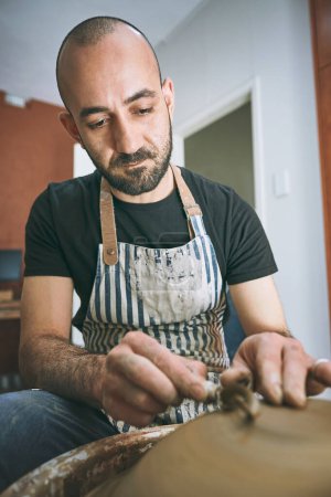 Photo for Isnt it more fun making a gift than buying one. a young man working with clay in a pottery studio - Royalty Free Image