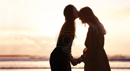 Téléchargez les photos : Ce dont le monde a besoin, c'est d'amour et de paix. deux jeunes femmes passent la journée à la plage au coucher du soleil - en image libre de droit