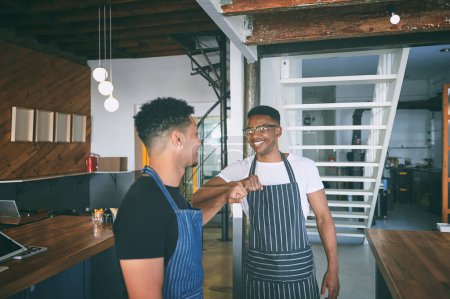Photo for Buddies in life and in business. two confident young men giving each other a fist bump while working in a cafe - Royalty Free Image
