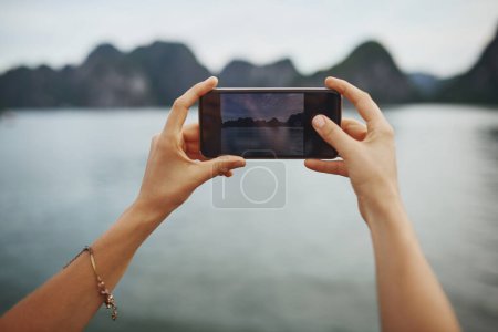 Téléchargez les photos : Plus vous voyagez, plus vous vous souvenez. une jeune femme prenant des photos d'une rivière au Vietnam avec son smartphone - en image libre de droit
