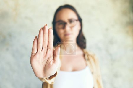 Photo for We have to put a stop to this. Portrait of a woman holding up her hand while standing against a wall - Royalty Free Image