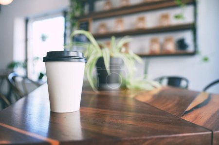 Photo for Your pick me up is ready to be picked up. a paper cup on a counter in an empty cafe - Royalty Free Image