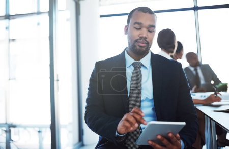 Téléchargez les photos : La façon intelligente de rendre les réunions plus productives. un jeune homme d'affaires utilisant une tablette numérique lors d'une réunion au travail - en image libre de droit