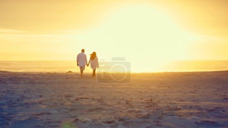 Photo for Walking hand in hand on the beach. Rearview shot of an affectionate mature couple walking hand in hand on the beach - Royalty Free Image