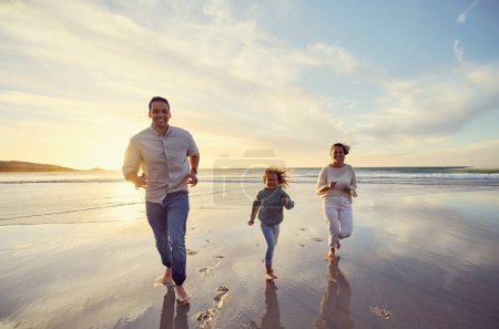 Photo for Mother, father and girl on beach at sunset for family holiday, summer vacation and weekend. Nature, travel and happy mom, dad and child running in ocean waves for bonding, playing and quality time. - Royalty Free Image