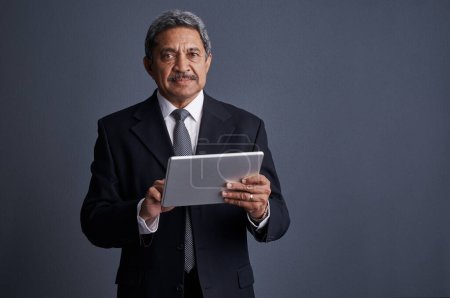 Photo for Its an opportunity to think bigger. Studio shot of a mature businessman using his digital tablet - Royalty Free Image