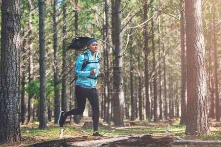 Photo for Take care of your body. Full length shot of an athletic young woman out for a jog in the woods - Royalty Free Image