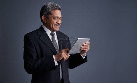 Photo for This device allows me to have more free time. Studio shot of a mature businessman using his digital tablet - Royalty Free Image