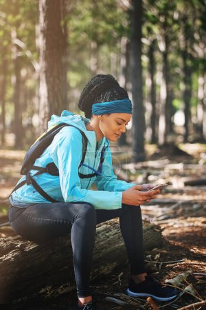 Photo for If it wasnt hard, everyone would do it. an athletic young woman sending a text while jogging in the woods - Royalty Free Image