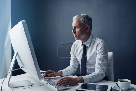 Téléchargez les photos : Il a un boulot à faire. un homme d'affaires mature travaillant sur son ordinateur - en image libre de droit