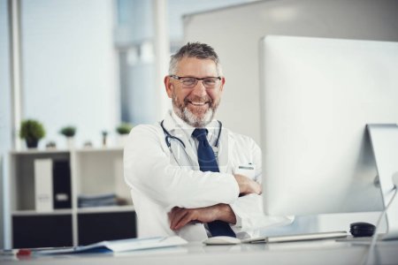 Foto de Lo mejor en el negocio de la medicina. Retrato de un médico maduro usando una computadora en un escritorio en su oficina - Imagen libre de derechos