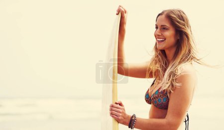 Foto de Es hora de enseñarles una lección a estas olas. una joven atractiva parada en una playa con una tabla de surf - Imagen libre de derechos