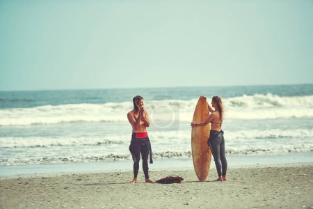 Téléchargez les photos : Chaque jour devrait être jour de surf. un jeune couple surfant sur la plage - en image libre de droit