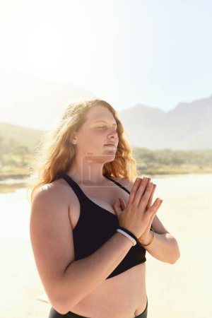 Foto de El yoga nos ayuda a mantener un estado de calma interior. una hermosa joven practicando yoga en la playa - Imagen libre de derechos