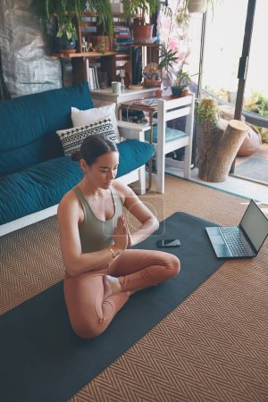 Foto de El zen es lo que busco. una joven meditando mientras practica yoga en casa - Imagen libre de derechos