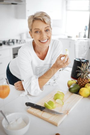 Photo for Portrait, fruit salad and apple with an old woman in the kitchen of her home for health, diet or nutrition. Smile, food and cooking with a happy mature female pensioner eating healthy in the house. - Royalty Free Image