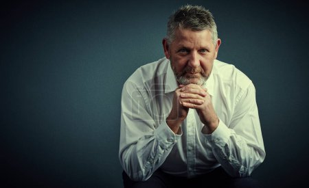 Photo for Let me give you some advice. Studio portrait of a handsome mature businessman looking thoughtful while sitting down against a dark background - Royalty Free Image