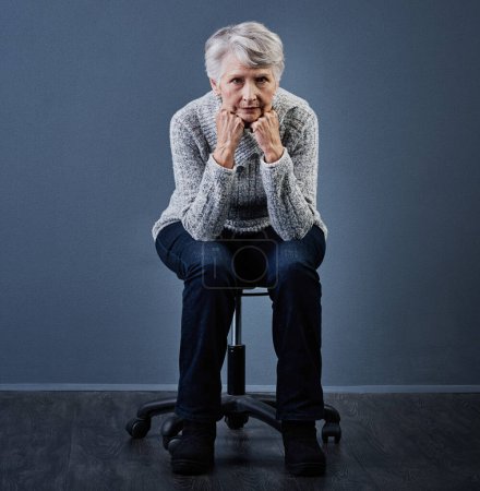 Photo for If looks could kill. Studio shot of an elderly woman sitting with her hands under her chin while looking at the camera - Royalty Free Image