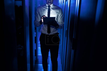 Photo for Performing a few administrative duties while monitoring data. Closeup shot of an unrecognisable man using a digital tablet while working in a server room - Royalty Free Image