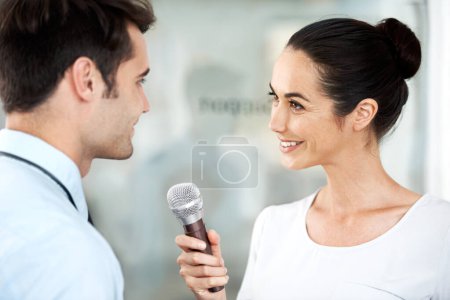 Photo for Care to answer a few quick questions. Young executive being interviewed by a reporter with a microphone - Royalty Free Image
