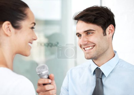 Foto de Dinos tu consejo para otros empresarios. Un joven ejecutivo siendo entrevistado por un reportero con un micrófono - Imagen libre de derechos