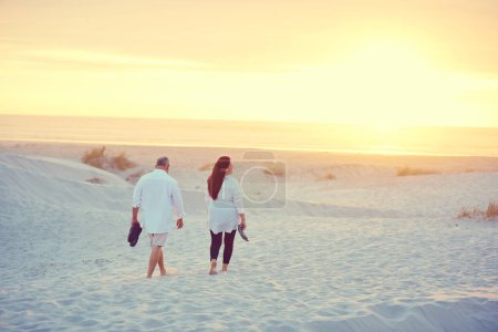 Téléchargez les photos : Promenades tranquilles le long de la plage. un couple d'âge mûr faisant une promenade relaxante sur la plage - en image libre de droit