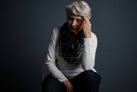 Photo for Pain does come with age sometimes. Studio shot of a stressed out elderly woman sitting down with her eyes closed and contemplating - Royalty Free Image