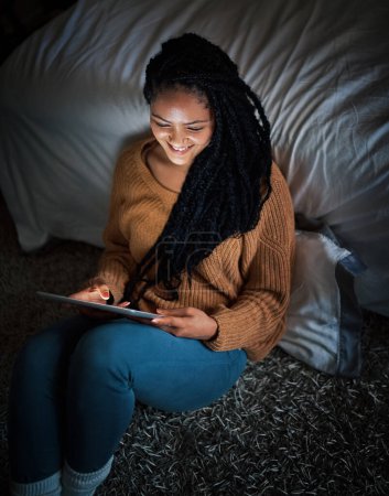 Téléchargez les photos : Dernier post sur les réseaux sociaux pour la journée. une jeune femme détendue utilisant une tablette numérique pendant la soirée à la maison - en image libre de droit