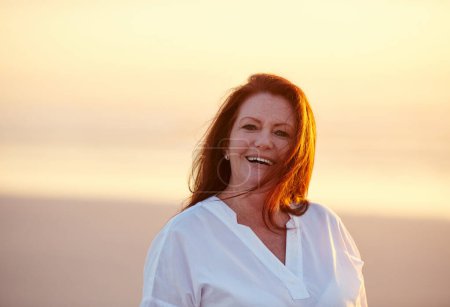 Téléchargez les photos : Le bonheur est une vacance instantanée. femme mature debout sur la plage au coucher du soleil - en image libre de droit