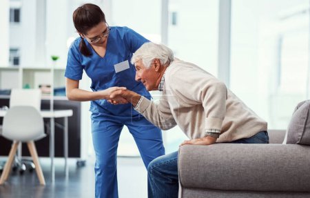 Téléchargez les photos : Il a juste besoin d'aide. une jeune infirmière aidant sa patiente âgée à se relever d'une chaise dans la maison de retraite - en image libre de droit