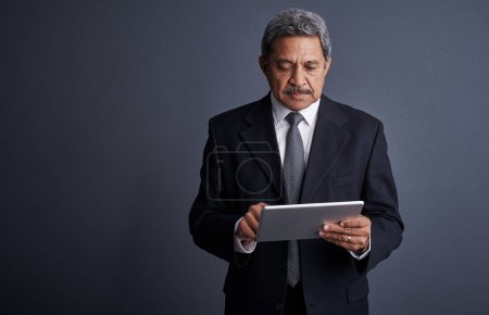 Photo for This device taught me more than years of experience. Studio shot of a mature businessman using his digital tablet - Royalty Free Image