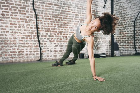 Téléchargez les photos : Inclure des planches latérales dans votre routine d'exercice de base. une jeune femme sportive faisant la planche latérale à la salle de gym - en image libre de droit