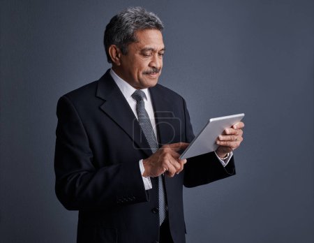 Foto de Administre todos los aspectos de su negocio desde su dispositivo. Estudio de un hombre de negocios maduro usando su tableta digital - Imagen libre de derechos