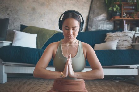 Téléchargez les photos : Méditer aide à améliorer votre concentration. une jeune femme méditant tout en pratiquant le yoga à la maison - en image libre de droit