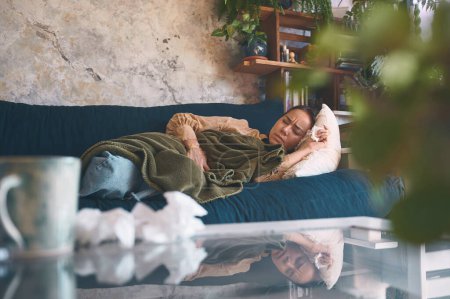 Foto de Estar enfermo es tu forma de llamar tu atención. una mujer joven que experimenta dolor de estómago mientras está acostada en el sofá en casa - Imagen libre de derechos