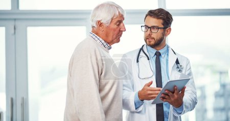 Photo for Keeping his patients well informed. a doctor discussing something on a digital tablet with a senior patient in a clinic - Royalty Free Image