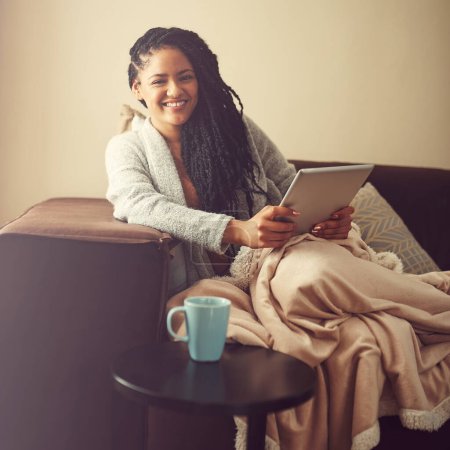 Téléchargez les photos : Fais en sorte que ton jour de congé compte. une jeune femme utilisant sa tablette tout en se relaxant à la maison - en image libre de droit