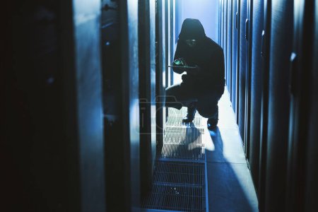Photo for Stealing all of your data. a hacker using a digital tablet in a server room - Royalty Free Image