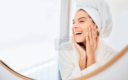 Foto de Espejo, mujer feliz y las manos en la cara para el cuidado de la piel, sonrisa y anti envejecimiento resultado cosmético en el baño. Facial, belleza y tacto femenino piel suave, brillante o lisa de la rutina de dermatología de lujo en el hogar. - Imagen libre de derechos