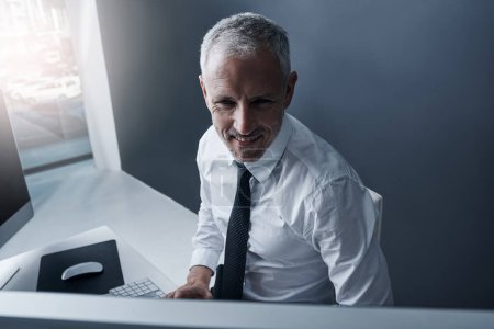 Téléchargez les photos : Technologie intelligente pour l'homme d'affaires intelligent. un homme d'affaires concentré travaillant derrière son ordinateur dans le bureau - en image libre de droit