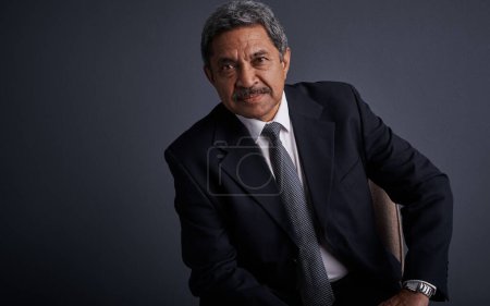 Photo for People look up to him in the business sector. Studio shot of a mature businessman posing against a dark background - Royalty Free Image