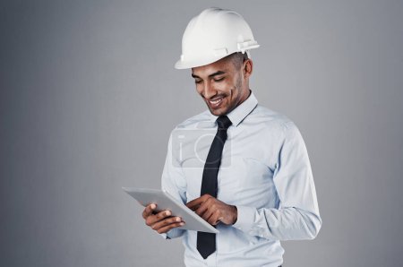 Photo for Its all coming together now. a well-dressed civil engineer using his tablet while standing in the studio - Royalty Free Image