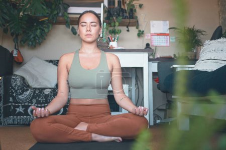Foto de Trabaja en construir una mejor conexión contigo mismo. una joven meditando mientras practica yoga en casa - Imagen libre de derechos